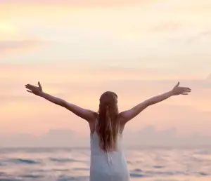 Image a girl with outstretched arms at a beach symbolizing freedom, like the freedom you can experience when EFT complements chiropractic in London Ontario.