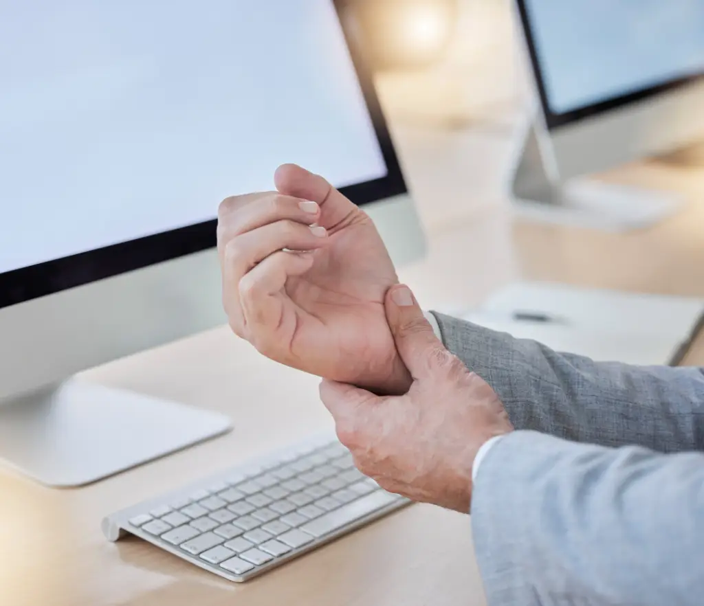 Man holding wrist in pain at a keyboard, seeking carpal tunnel relief in London Ontario with chiropractic care.