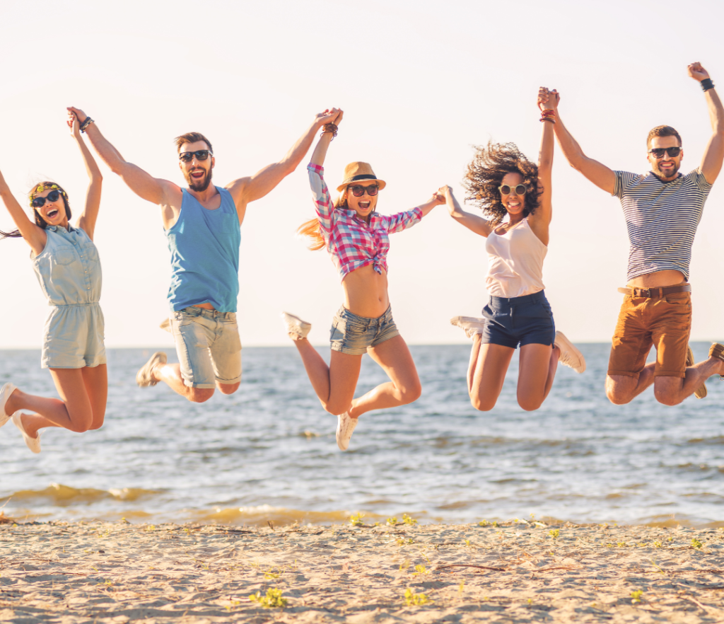 Group of young adults having fun and jumping at the beach, showing the benefits of chiropractic care for summer in London Ontario.