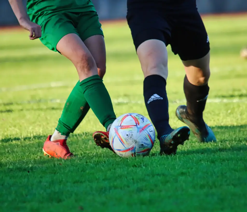 Improve athletic performance with chiropractic care as two athletes kick a soccer ball during a game.