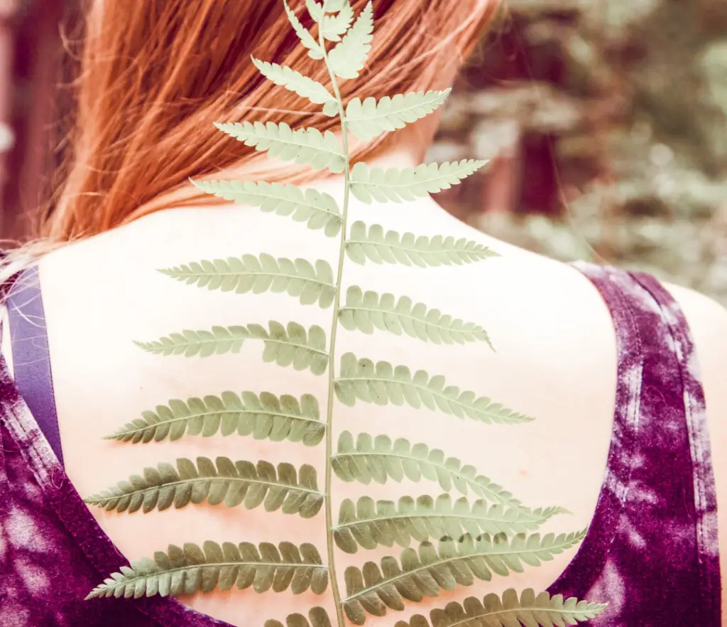 Back of a girl with a fern leaf showing scoliosis curve, symbolizing natural scoliosis care in London Ontario.