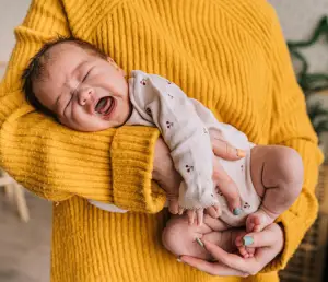 Postpartum chiropractic care in London Ontario – A baby crying in a mother’s arms, symbolizing the stress new mothers face and the potential benefits of chiropractic care.