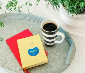 Cup of coffee on a tray with a plant and a yellow gratitude journal, symbolizing the gift of gratitude in London Ontario.