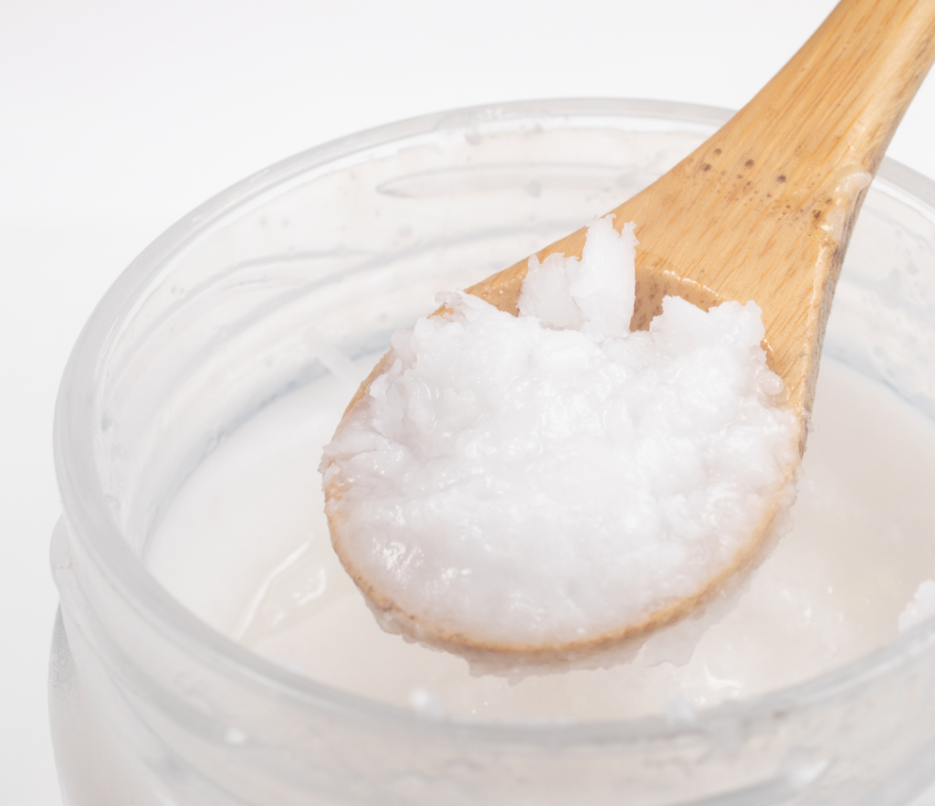 Glass jar of coconut oil with a wooden spoon, highlighting the natural ingredients used for oil pulling.